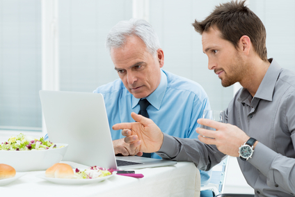 Two Business People Working On Laptop at Lunch In Restaurant